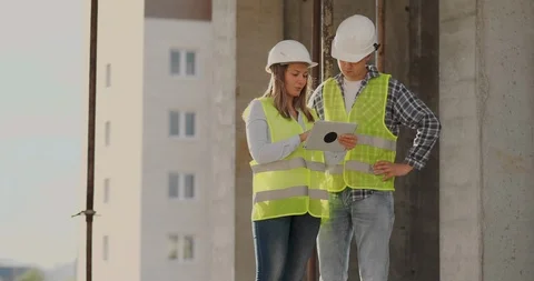 Construction worker man and architect woman in a helmet, discuss the plan of Video stock 112336363