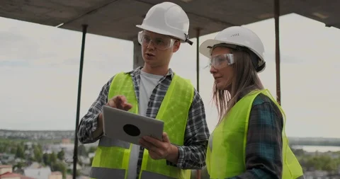 Construction worker man and architect woman in a helmet, discuss the plan of Video stock 112337804