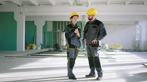 Construction worker man and engineer woman standing in a large space building Stock Footage 199441939