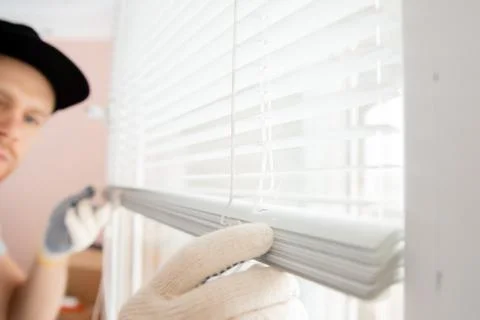 Construction worker man install blinds on plastic white upvc windows in house 스톡 사진