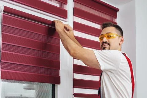 Construction worker man in a uniform install blinds look at camera and smiling Foto stock