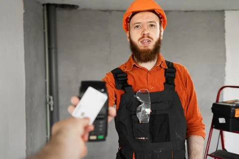 Construction worker man in workwear putting payment credit card with wirele.. Stock Photos