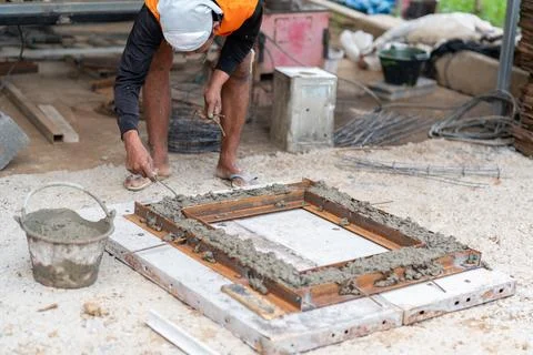 Construction worker manually inserting binding wire into a metal steel mold.. Fotos Stock