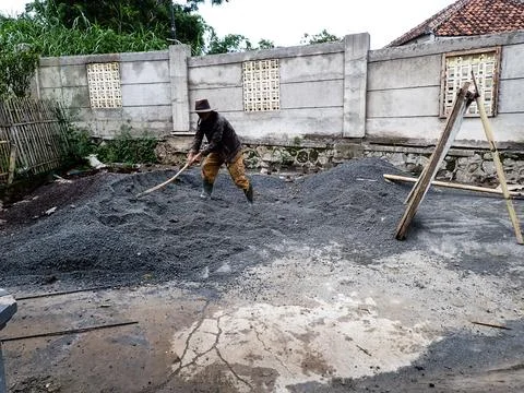 A construction worker manually sifts sand and gravel at a project site. Stock Photos