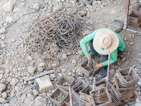 A construction worker manually tying steel rebar stirrups. Foto stock