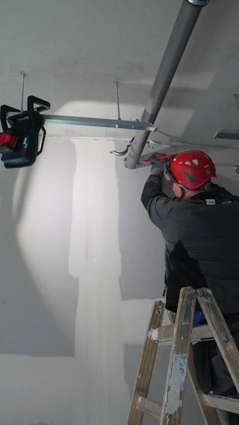 Construction worker marking ceiling pipe and bracket position during interior Stock Footage 331305224