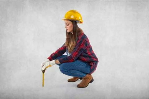 A construction worker measures something small, symbolic Stock Photos