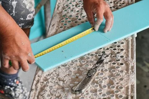 Construction worker measuring insulation foam piece with tape measure, clos.. Stock Photos