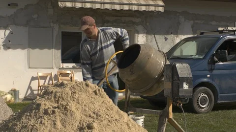 Construction worker mixes concrete in concrete mixer 動画素材 99881155
