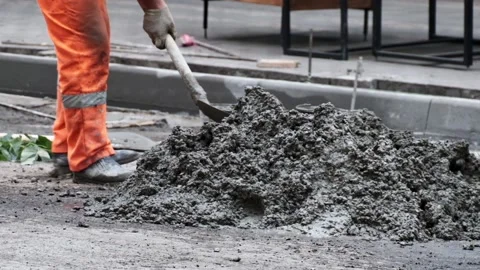Construction worker mixes grey cement holding shovel on ground slow motion close Vidéo 146572571
