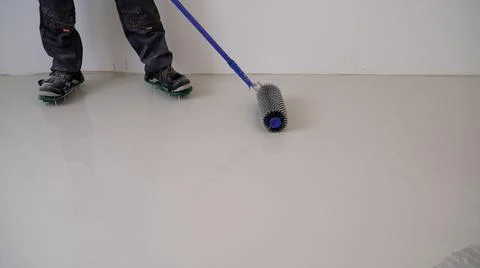Construction worker mixes leveling compound, putties the floor and prepares t Stock Photos