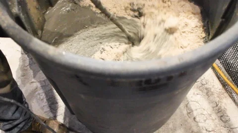 Construction worker mixes liquid concrete with electrical drill tool B Stock Footage 125057069