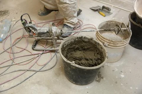 The construction worker mixes tile adhesive together with the water in the corre Fotos de archivo