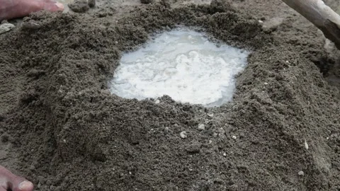 A construction worker mixing cement and sand using a hoe Stock Footage 307557581