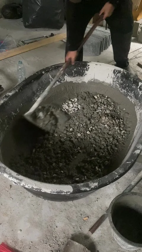 Construction worker mixing cement mortar with shovel at building site. Video stock 332566381