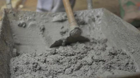 Construction worker mixing cement on pushcart using a hoe Stock Footage 255684444
