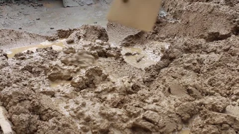 Construction worker mixing cement using a hoe Stock Footage 255684460