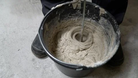 Construction worker mixing gray epoxy resin in a bucket Foto stock
