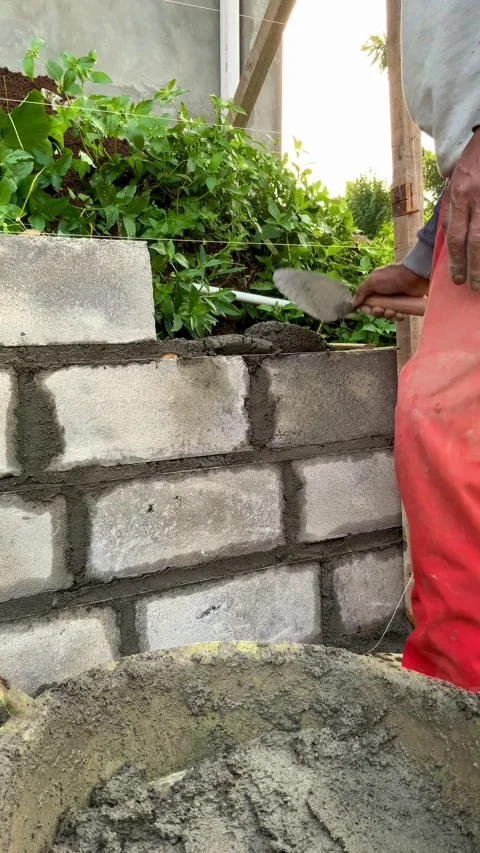 Construction worker mixing mortar with a trowel in a plastic bucket at a buildin Stock Footage 336097967