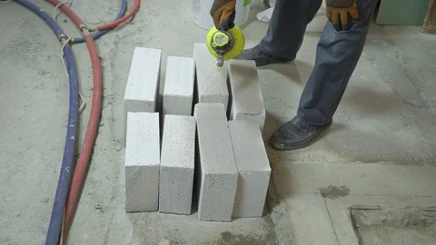 Construction worker moisturing aerated concrete blocks with water sprayer Stock Footage 102168230