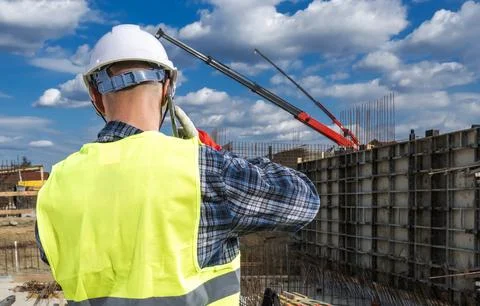 Construction worker monitors project at a site on a sunny day Stock Photos