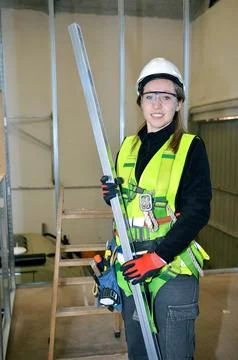 Construction worker mounting plasterboard with metal studs and protective gea Stock Photos