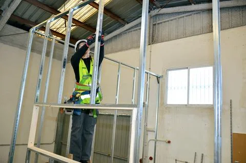Construction worker mounting plasterboard on metal frame Stock Photos