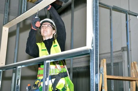 Construction worker mounting plasterboard on metal frame Stock Photos