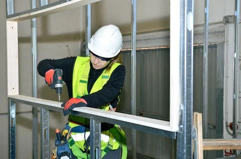 Construction worker mounting plasterboard on metal frame Stock Photos