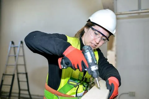 Construction worker mounting plasterboard with power drill Stock Photos