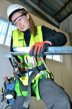 Construction worker mounting plasterboard using metal profiles and pliers Stock Photos