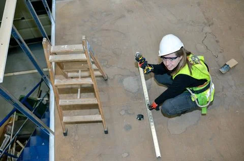 Construction worker mounting plasterboard using a level, drill and screws Stock Photos