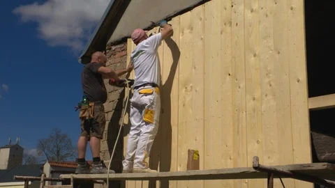 Construction worker nails boards with nailing machine Stock Footage 99889590