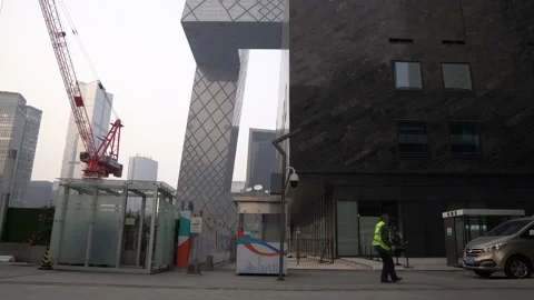 A construction worker next to CCTV headquarters building and cars in Beijing Stock Footage 234313957