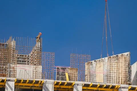 Construction worker observing crane lifting a concrete panel with rebar Stock Photos