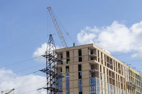 Construction Worker Operates Crane at Building Site Under Blue Sky With Clo.. Stock Photos