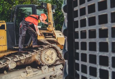 Construction Worker Operates Heavy Machinery on a Job Site During the Day Stock Photos