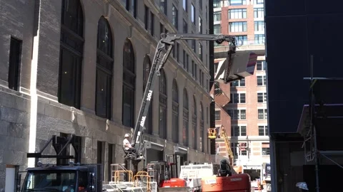 Construction worker operates a large hydraulic boom crane to lift building Stock Footage 334689898
