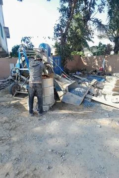 Construction worker operating blue concrete mixer on building site in Ghana Stock Photos