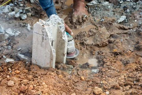 Construction worker operating grinder in wet soil job site action industria.. Foto stock