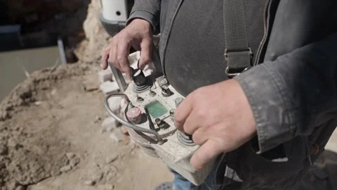 Construction worker operating heavy machinery with a remote control Stockbeeldmateriaal 334030219