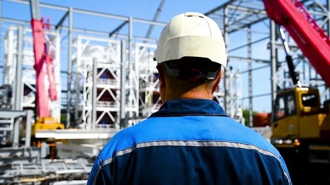 Construction worker or engineer in a hard hat and work clothes stands with .. Stock Footage 324854457