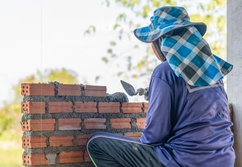 A construction worker, or mason, seen from the back, diligently lays a cour.. Stock Photos