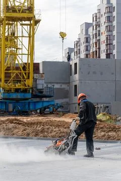Construction worker in orange helmet cutting concrete slab with dust cloud Stock Photos