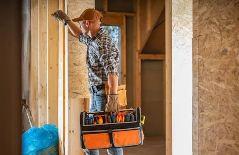 Construction Worker Organizing Tools Inside a New Home During Daylight Hours Foto stock