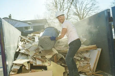 Construction Worker outside of house put old renovation material on big Stock-Fotos