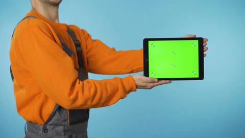 Construction worker in overalls presenting a product on greenscreen tablet Stock Footage 143698410
