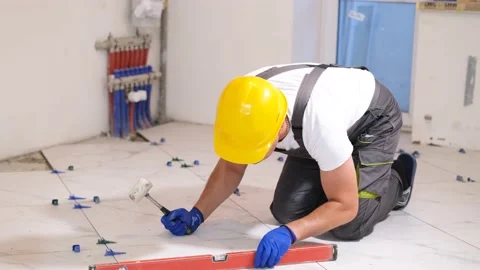 Construction worker in overalls sitting checks the quality level of flat floor Stock Footage 221361378