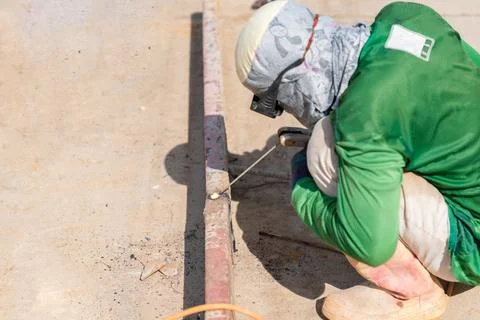 A construction worker is performing welding work on a metal beam at a const.. Stock Photos