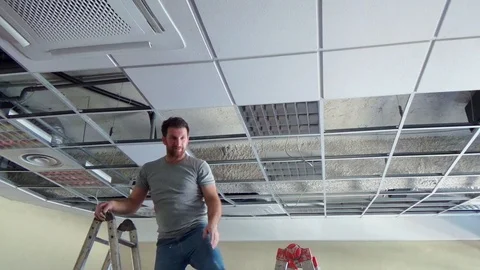 Construction worker performs a suspended ceiling maintenance with mineral fib Vídeo Stock 105575362